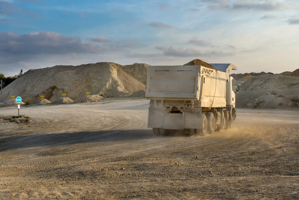 a white truck on a road on the background of piles of stone in a quarry, evening sky