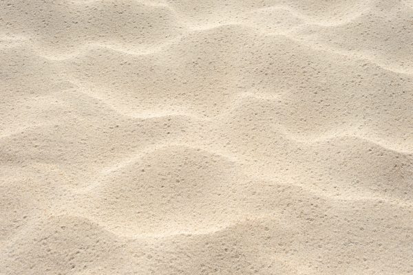 Beach sand texture. Summer background with a fragment of the seaside resort beach. Abstraction in nature